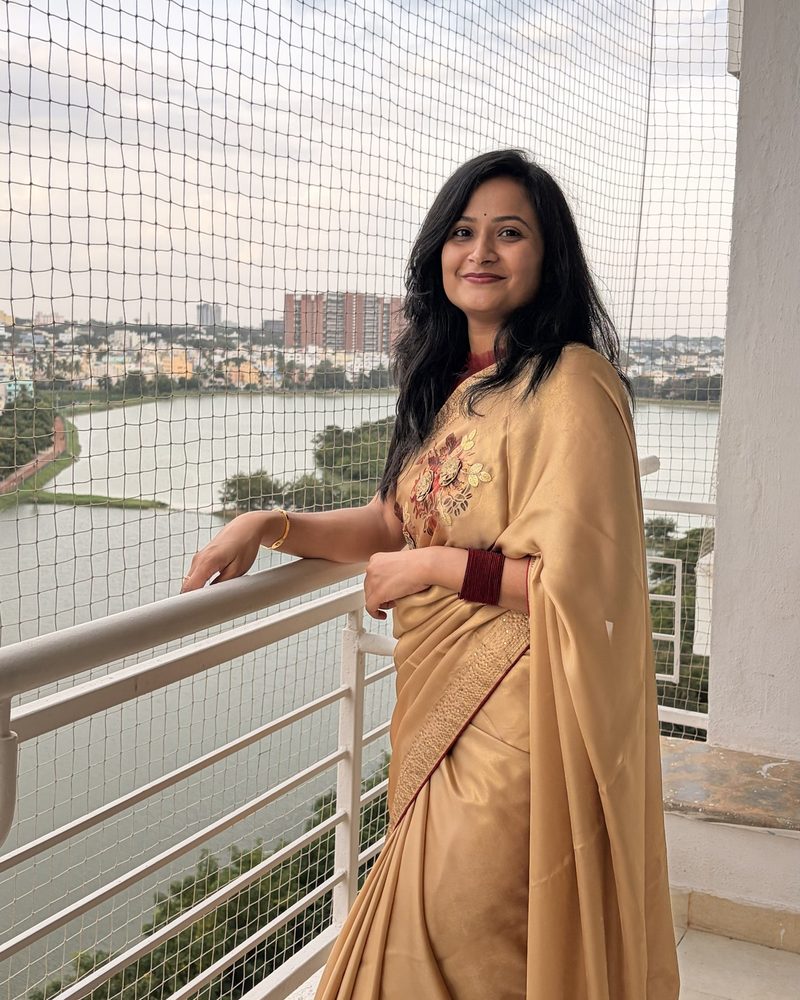 Manali in a gold saree on her balcony overlooking a Bangalore lake